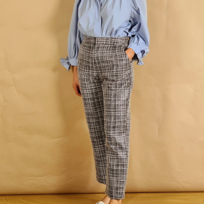 Model wearing blue and white boucle slim fit trousers with blue puff sleeve blouse side view