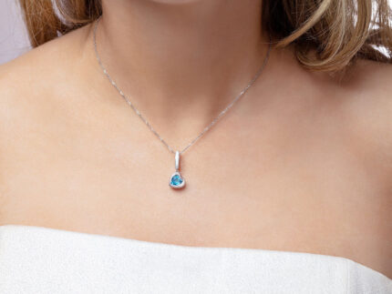 Our model wearing ‘Tradition with a twist’ charm with a heart Ostro Blue Topaz set in Sterling Silver on a necklace