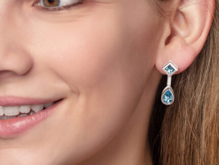 ‘Mix and Match’ earring drops with a pair of pear Ostro Blue Topaz set in sterling silver paired with our ‘Play by ear’ stud earrings with a pair of round Ostro Blue topaz set in Sterling Silver being worn by model