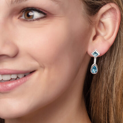 ‘Mix and Match’ earring drops with a pair of pear Ostro Blue Topaz set in sterling silver paired with our ‘Play by ear’ stud earrings with a pair of round Ostro Blue topaz set in Sterling Silver being worn by model