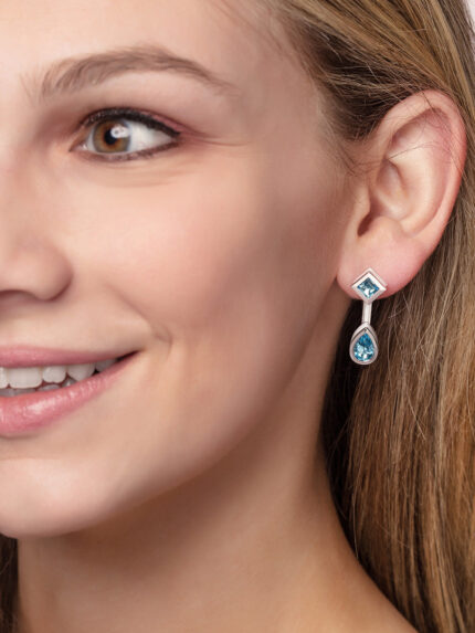 ‘Mix and Match’ earring drops with a pair of pear Ostro Blue Topaz set in sterling silver paired with our ‘Play by ear’ stud earrings with a pair of round Ostro Blue topaz set in Sterling Silver being worn by model