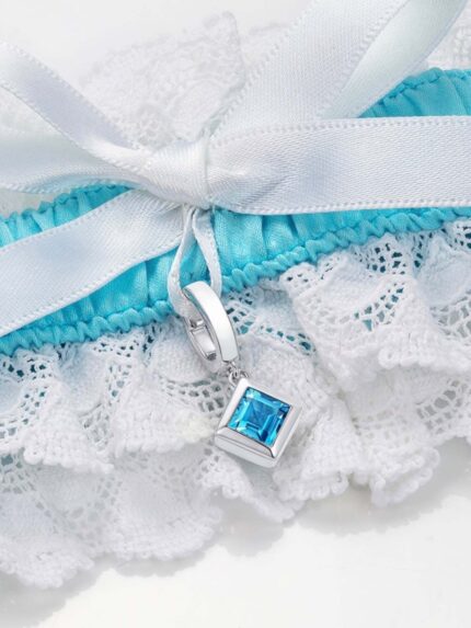 closeup of blue and white garter with square blue topaz charm