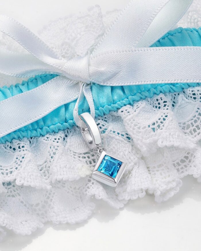 closeup of blue and white garter with square blue topaz charm