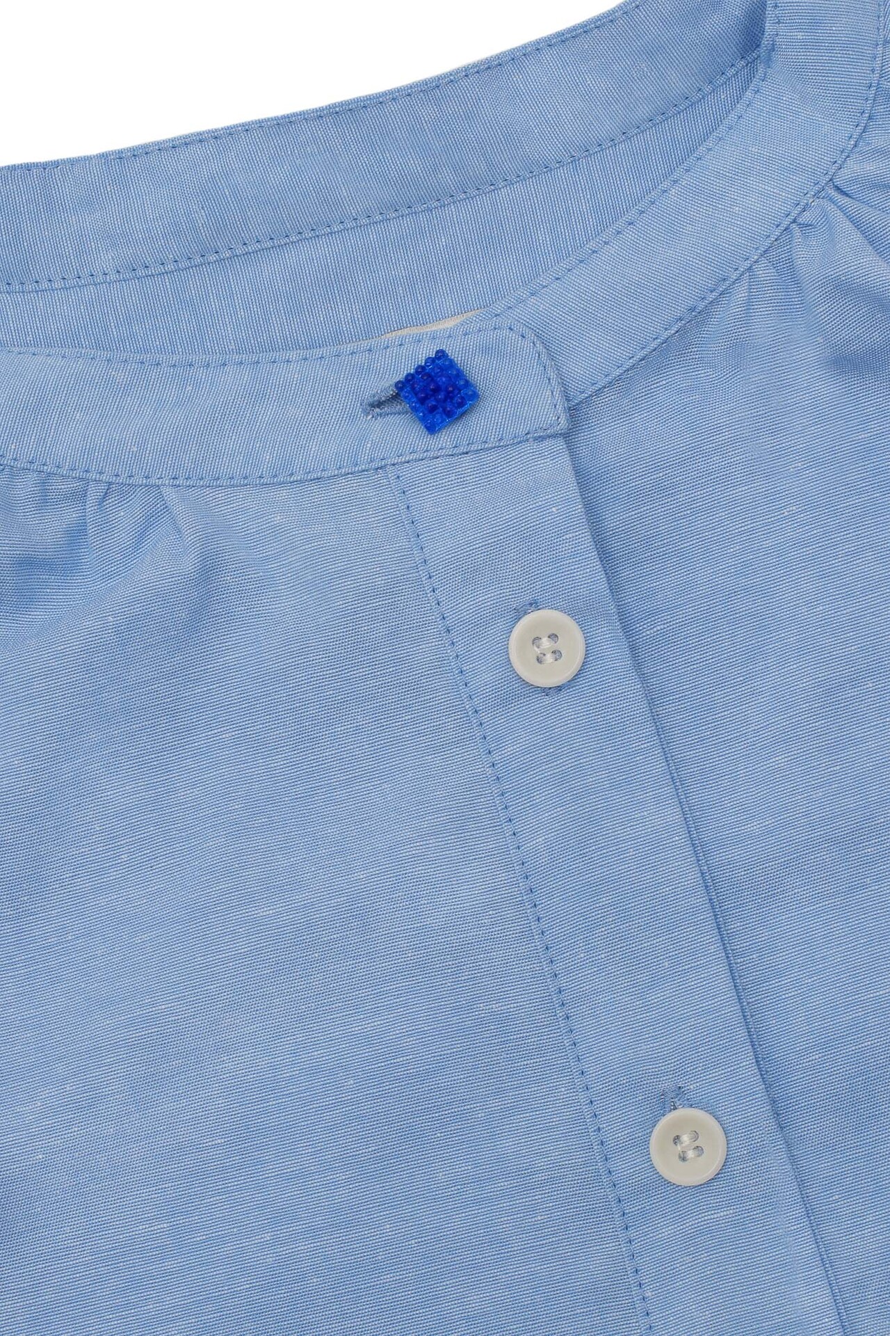 Close-up of Marie blouse gathered neck with vintage glass button detail, limited edition pale blue by Saywood