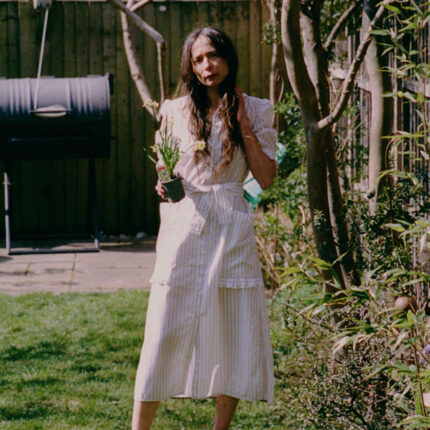 Lifestyle shot: Rosa puff sleeve shirtdress in white cotton pinstripe with ruffle pocket detail, made in London by Saywood