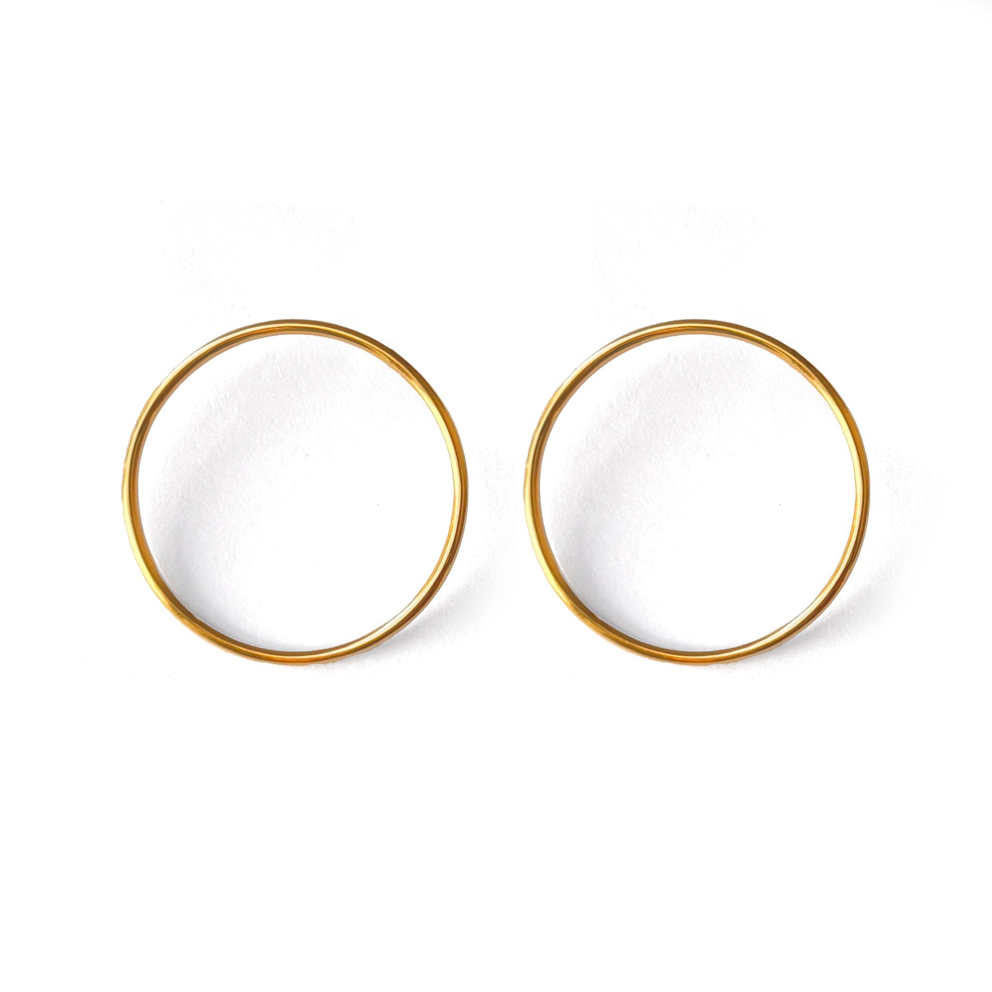 A pair of gold-colored circular earrings on a white background