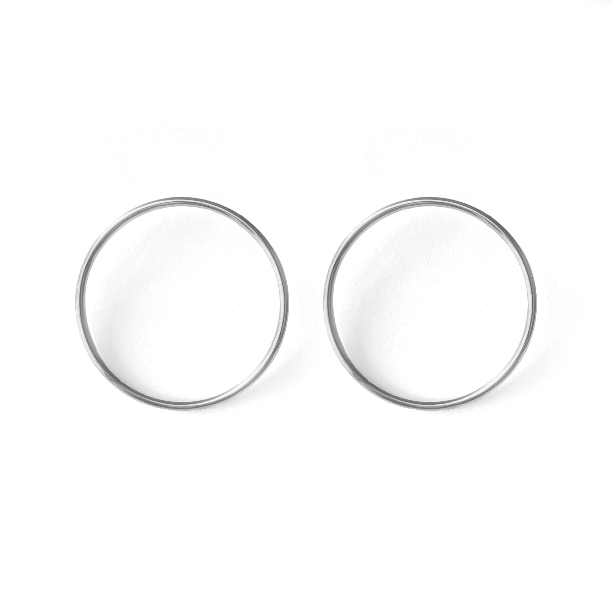 A pair of silver-colored circular earrings on a white background