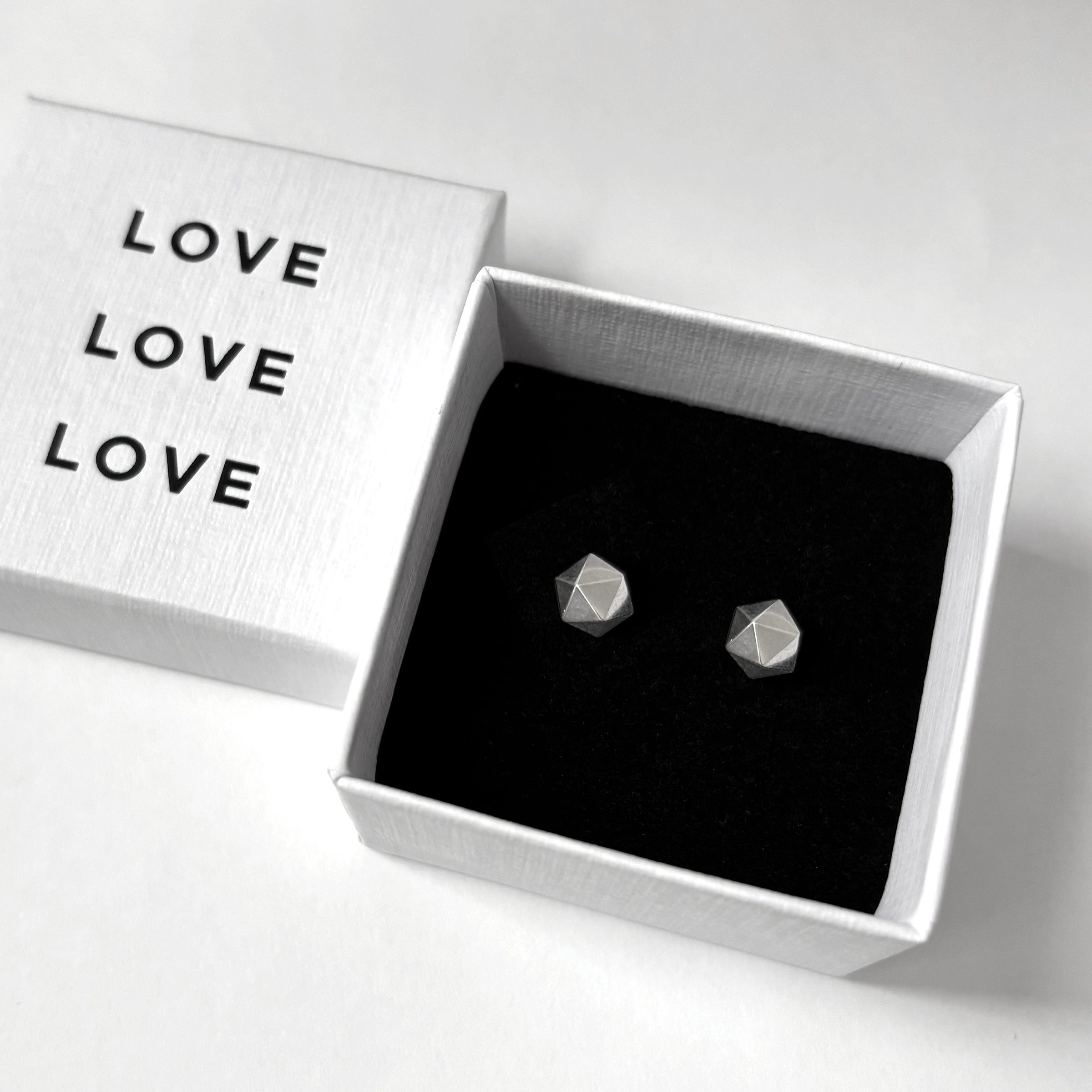 Geometric earrings in a box with 'LOVE' text on a white background