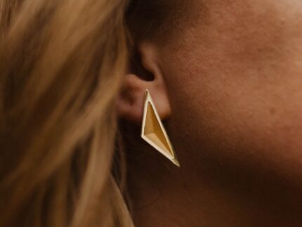 Close up of a person wearing a gold triangular earring