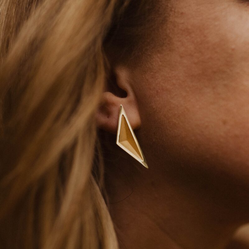 Close up of a person wearing a gold triangular earring