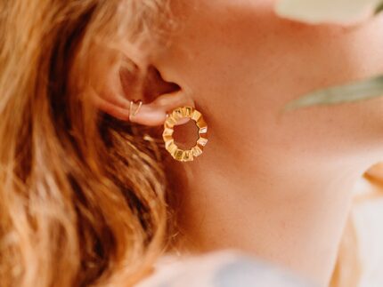 A pair of gold-colored modern geometric earrings with a faceted, circular design