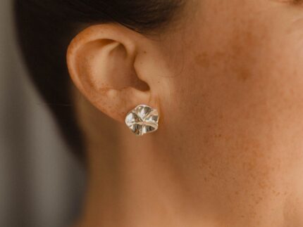 Close up of a person wearing a silver floral earring