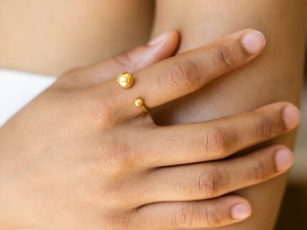 Close-up of a hand wearing a gold ring on a blurred background