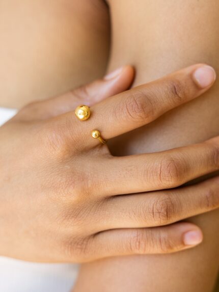 Close-up of a hand wearing a gold ring on a blurred background