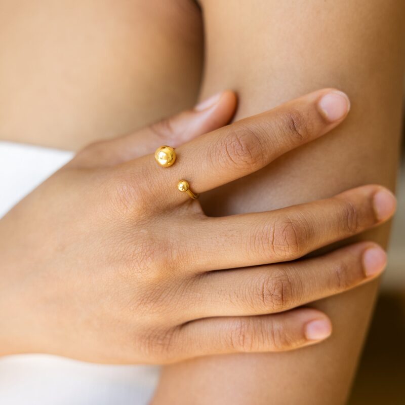 Close-up of a hand wearing a gold ring on a blurred background