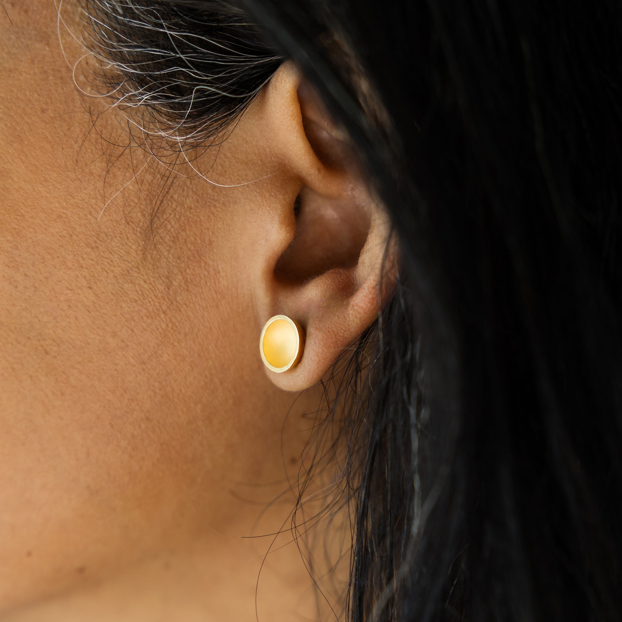Close-up of an ear wearing a gold earring