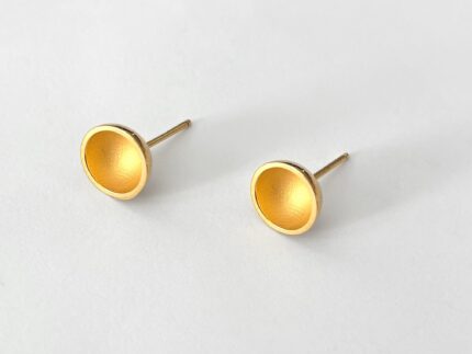 Pair of gold stud earrings on a light gray background