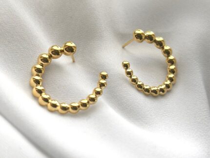 Gold hoop earrings on a white fabric background