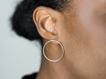 Close-up of a person wearing a hoop earring against a neutral background
