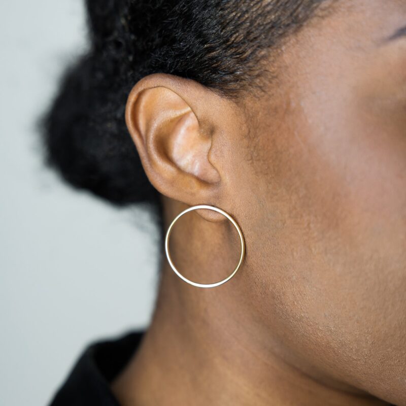 Close-up of a person wearing a hoop earring against a neutral background