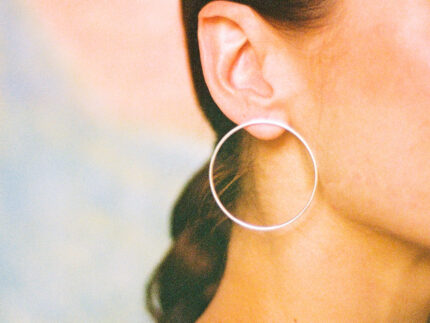 Close up of a person wearing a silver hoop earring against a blurred background