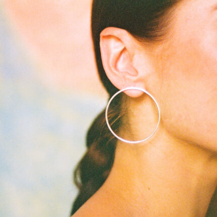 Close up of a person wearing a silver hoop earring against a blurred background