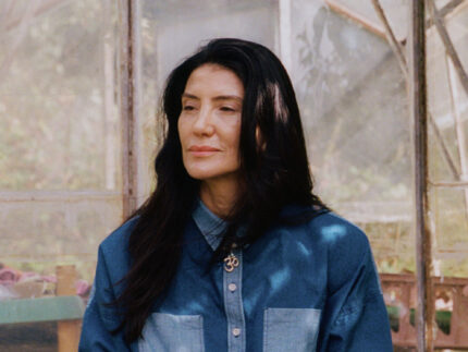 Woman with tea at greenhouse wearing Lela indigo Japanese denim patchwork shirt and Amelia trousers
