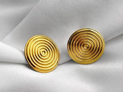 Pair of gold spiral earrings on a light gray fabric background