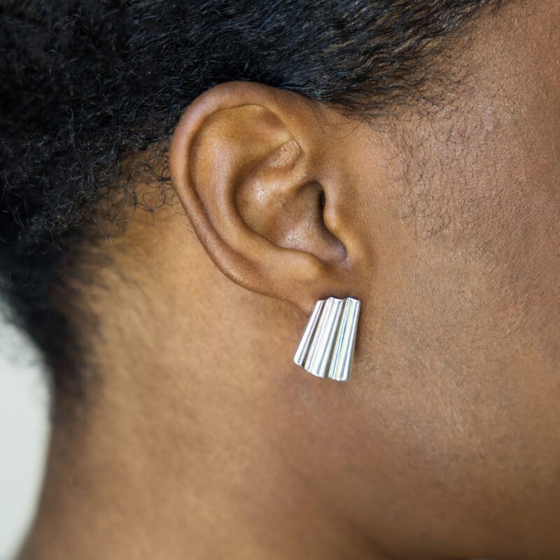 Close-up of an ear wearing a silver earring with a blurred background