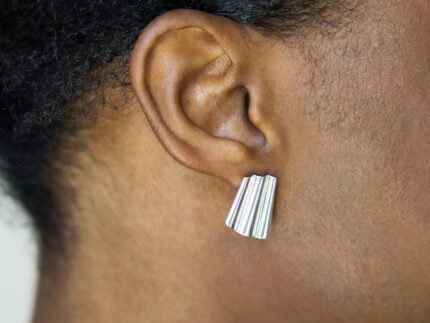 Close-up of an ear wearing a silver earring with a blurred background