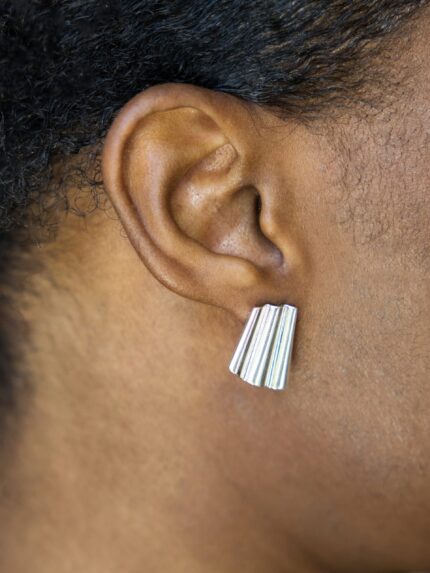 Close-up of an ear wearing a silver earring with a blurred background