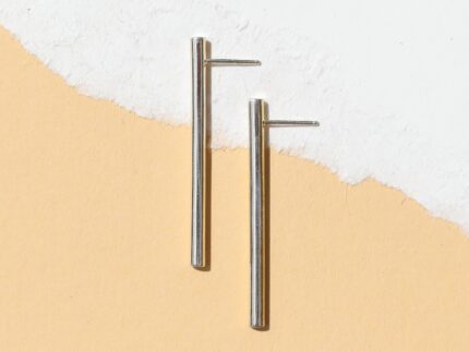 A pair of silver-colored linear drop line earrings with a tubular design, displayed against a white background.
