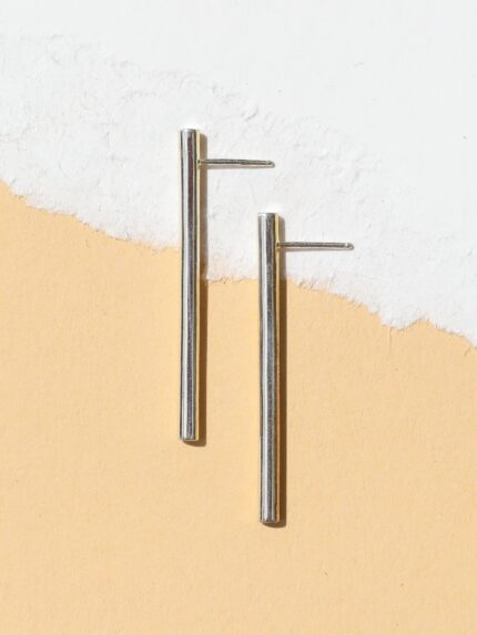 A pair of silver-colored linear drop line earrings with a tubular design, displayed against a white background.