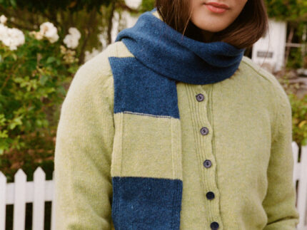 Model wearing an Atlantis blue ribbed beanie with pink trim, styled with a lime cardigan and blue and lime scarf.