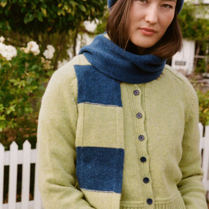 Model wearing an Atlantis blue ribbed beanie with pink trim, styled with a lime cardigan and blue and lime scarf.