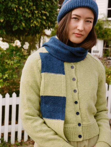 Model wearing an Atlantis blue ribbed beanie with pink trim, styled with a lime cardigan and blue and lime scarf.